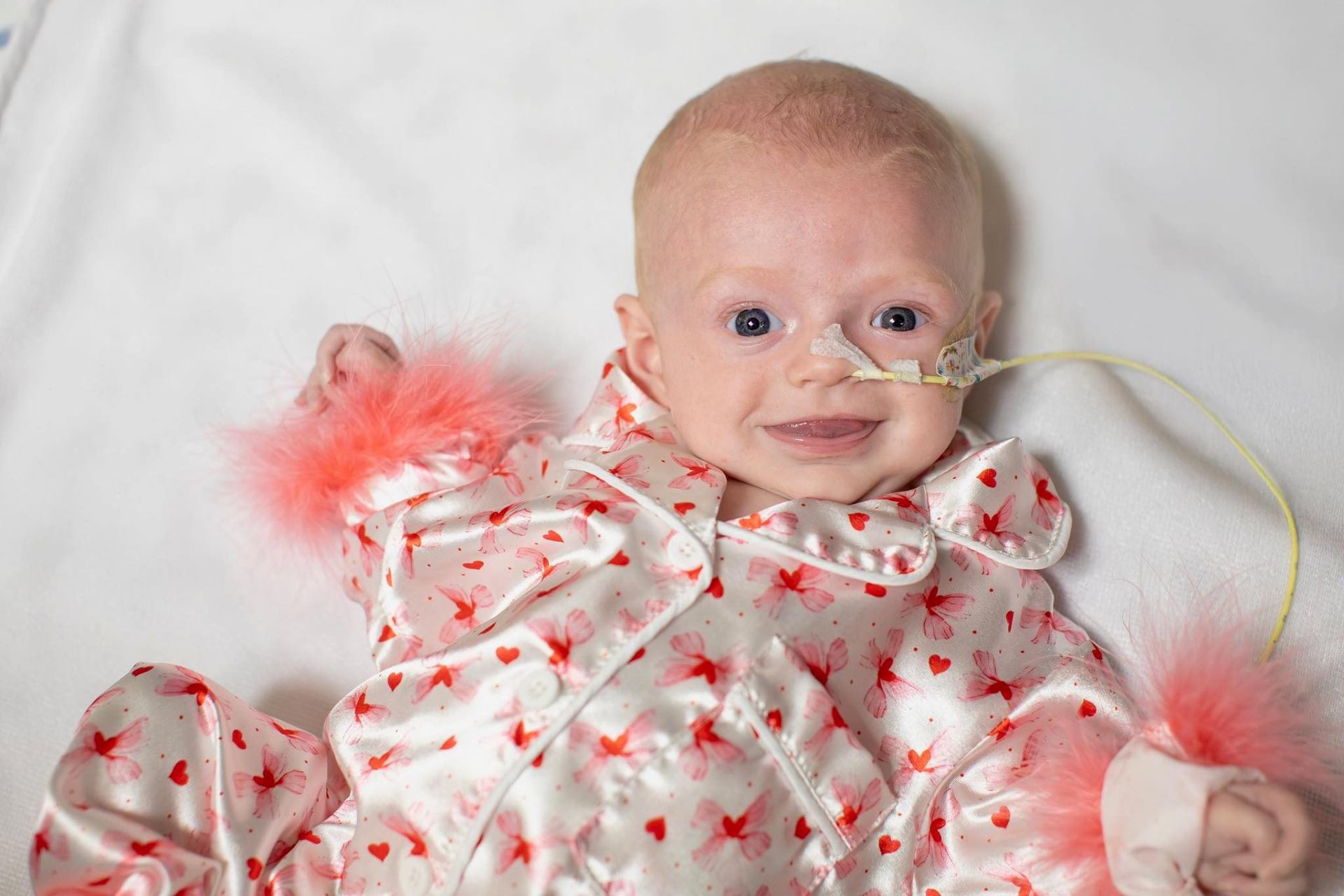 Augyst smiling in a pink heart-print outfit